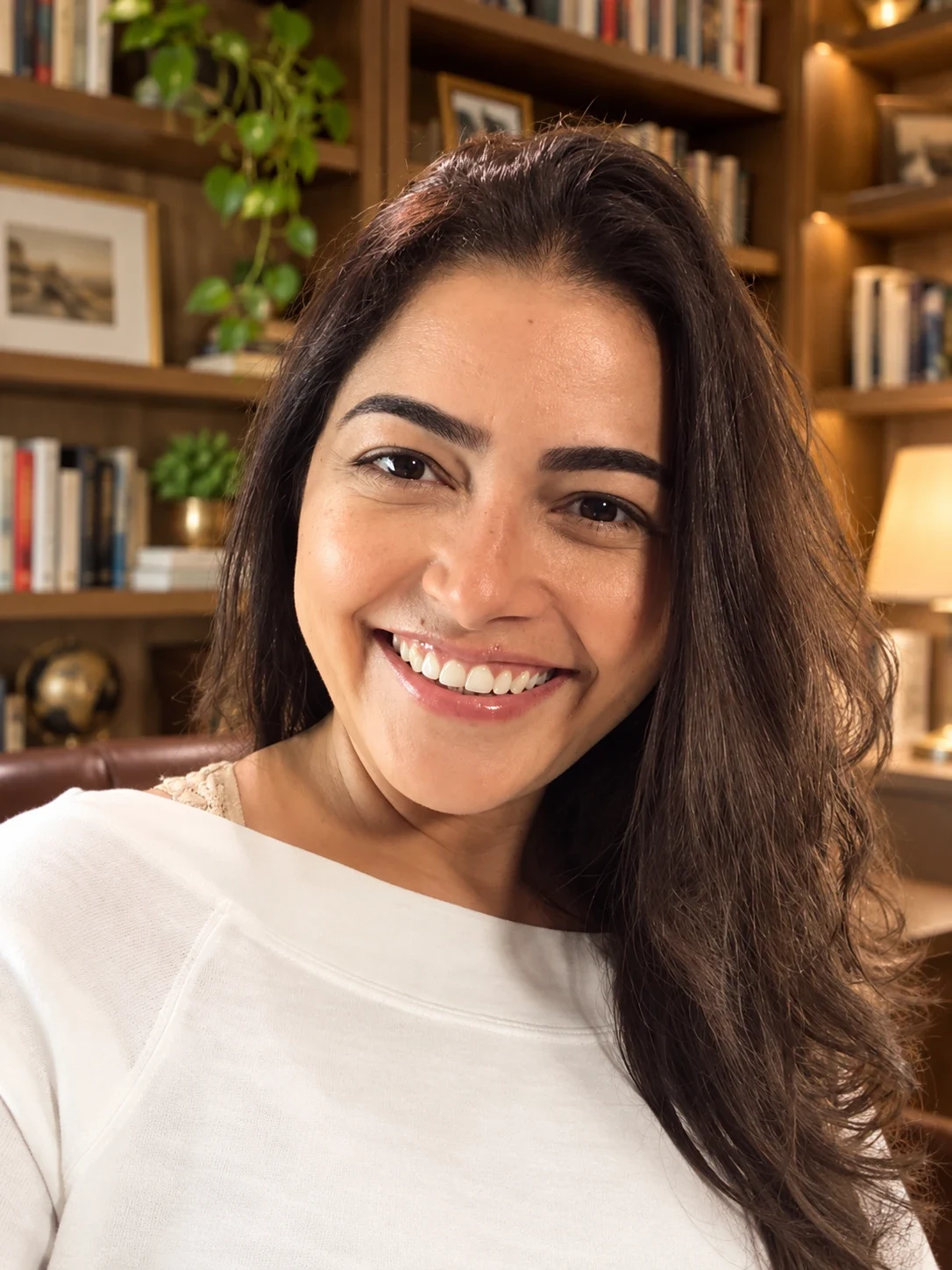 Juliana sorrindo diante de sua biblioteca.